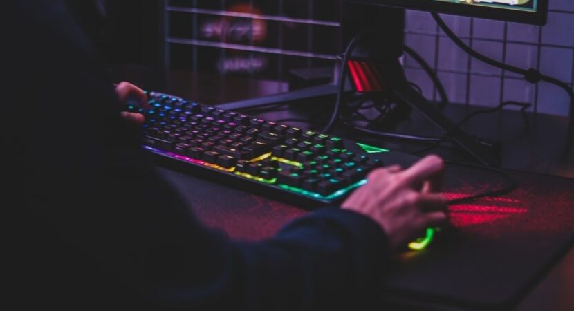 Joueur utilisant un clavier rétroéclairé et une souris devant un écran